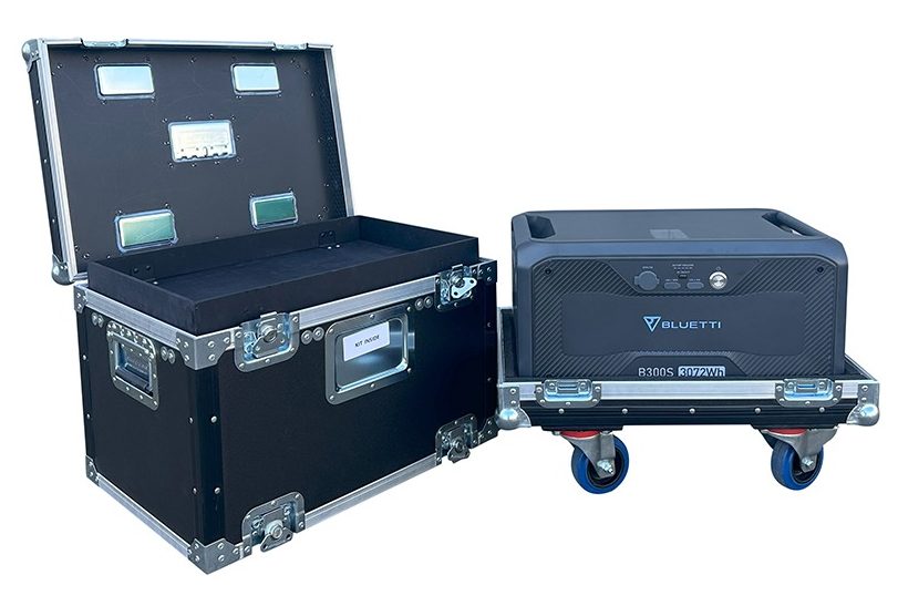 Open black flight case beside a Bluetti portable power station on a rolling cart.